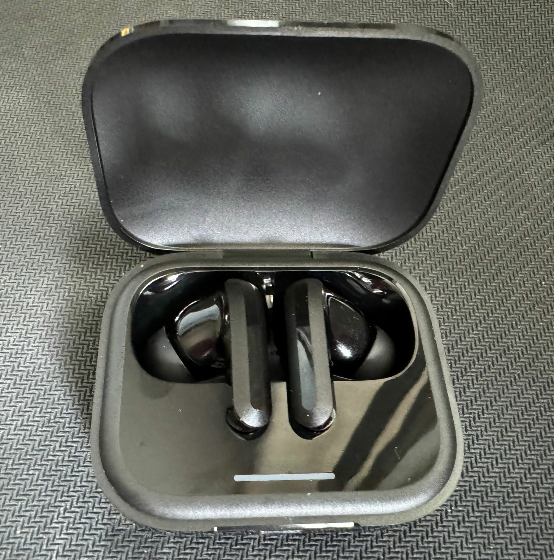 Xiaomi Buds 5 in Ladecase vor schwarzem strukturiertem Hintergrund